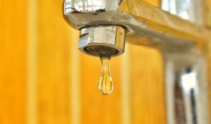 Photo robinet avec goutte sur fond jaune orangé