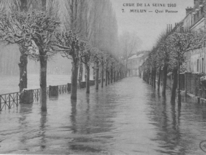 Photo en noir et blanc d'un quai arboré recouvert d'eau avec des habitations à droite.