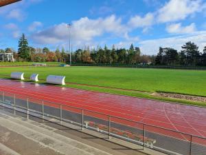 photo prise depuis les tribunes montrant un terrain en gazon naturel de bonne qualité avec la piste d'athlétisme au premier plan