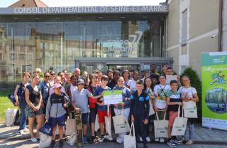 Un groupe de collégien pose devant l'Hôtel du Département avec son prix Collège Nature et des exemples d'hôtels à insectes réalisés et présentés par les élèves