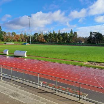 photo prise depuis les tribunes montrant un terrain en gazon naturel de bonne qualité avec la piste d'athlétisme au premier plan