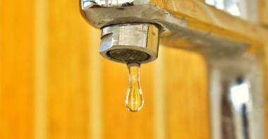 Photo robinet avec goutte sur fond jaune orangé