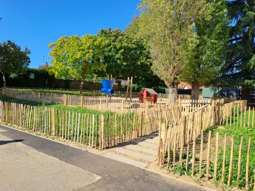 Espace enherbé et planté favorisant l'infiltration des eaux pluviales à l'école du Moulin Fleuri. De grands arbres sont déjà présents et des jeux sont installés. Des ganivelles en bois protègent temporairement l'accès.