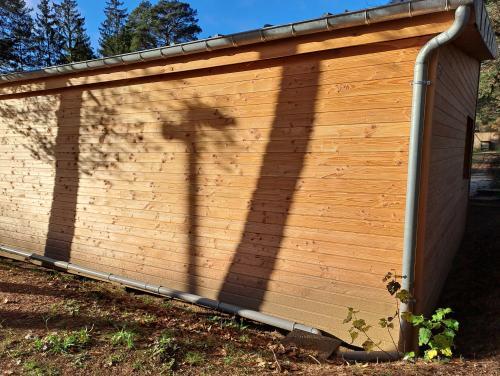 A l'arrière d'un bâtiment en bois neuf, deux gouttières convergent vers le sol