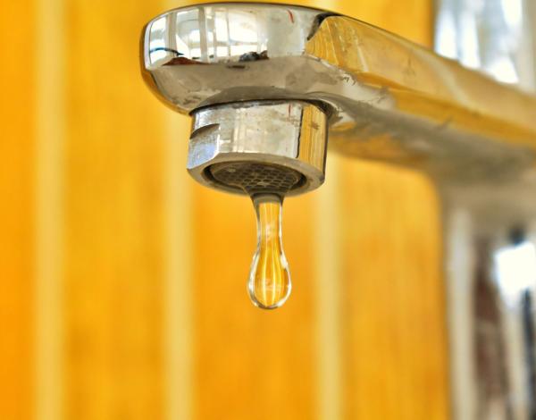 Photo robinet avec goutte sur fond jaune orangé